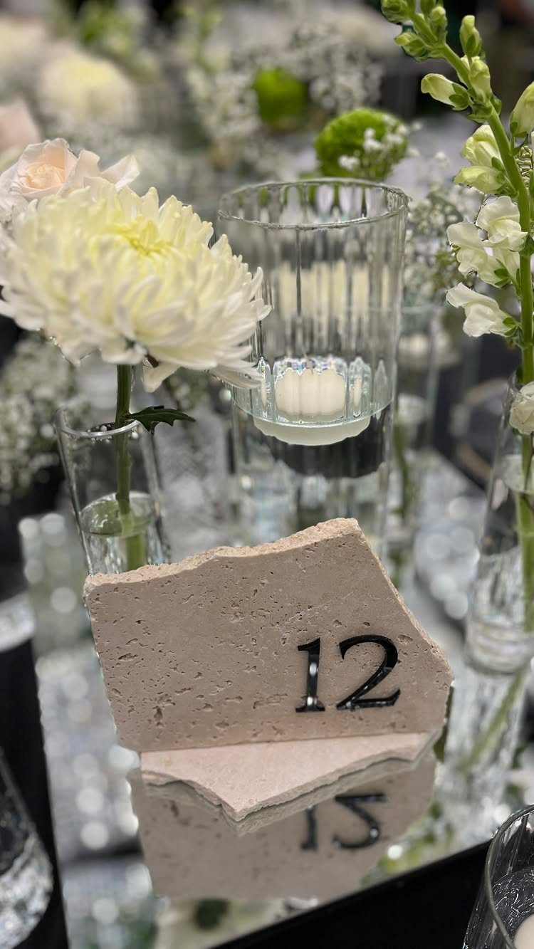Stone table number twelve with white flowers and candles on a mirrored table.