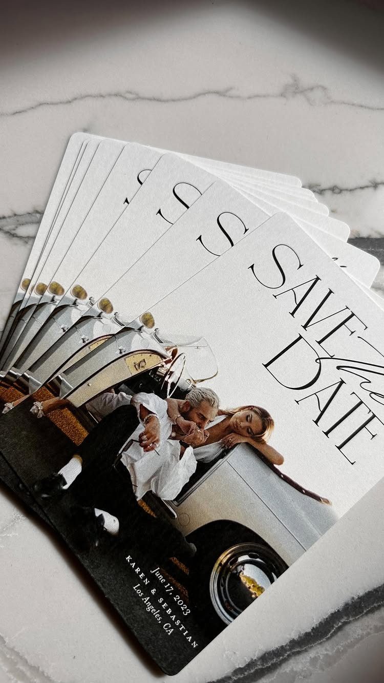 Stack of save-the-date cards featuring a couple with a white vintage car.