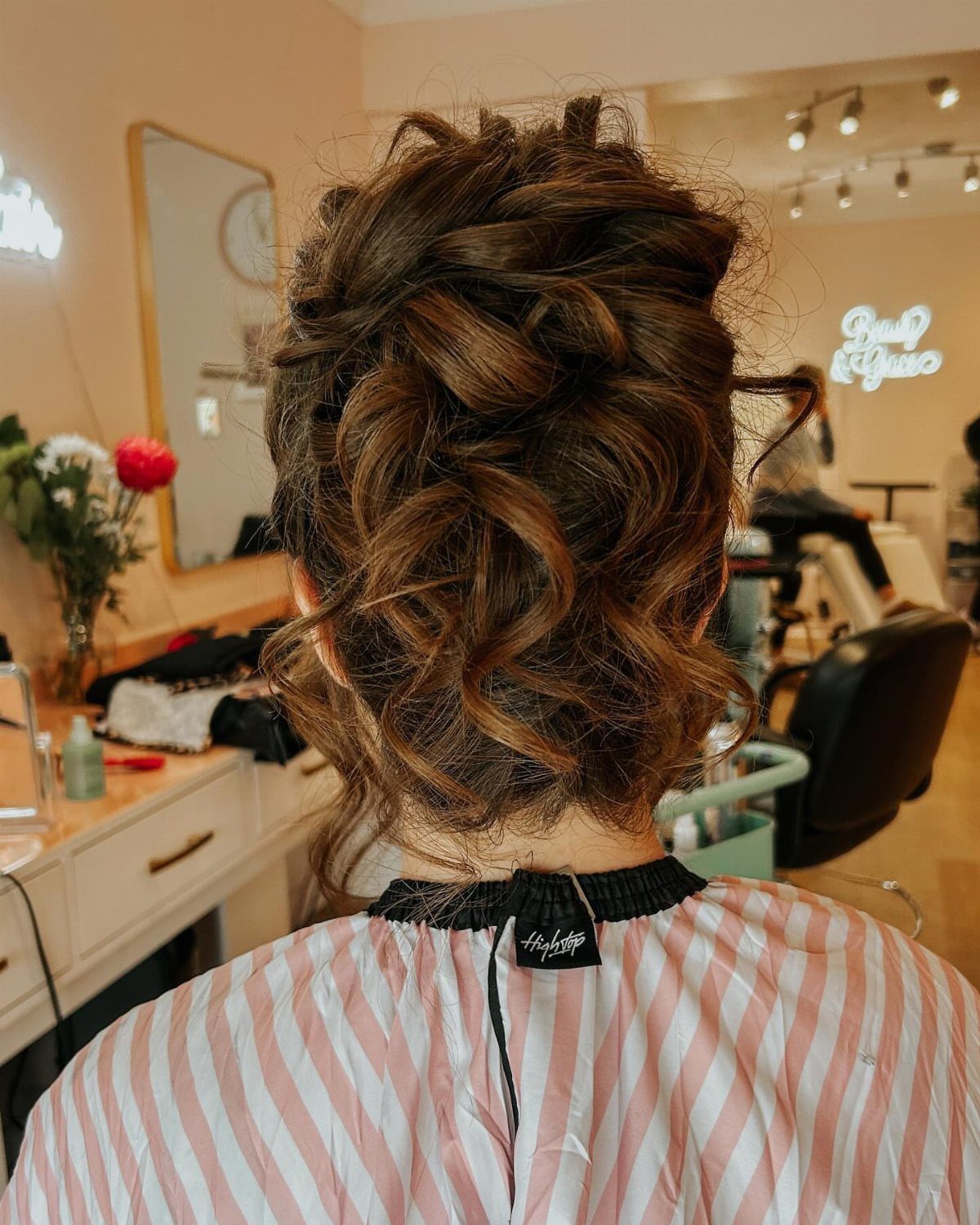 Intricate curly brown updo hairstyle on a woman in a beauty salon