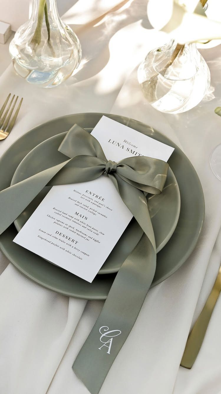 Sage green plate with a printed wedding menu tied with a satin ribbon.
