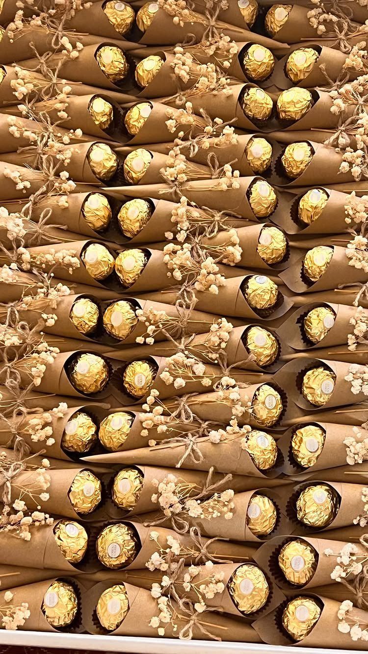 Gold wrapped chocolates in brown paper cones with white baby's breath flowers.