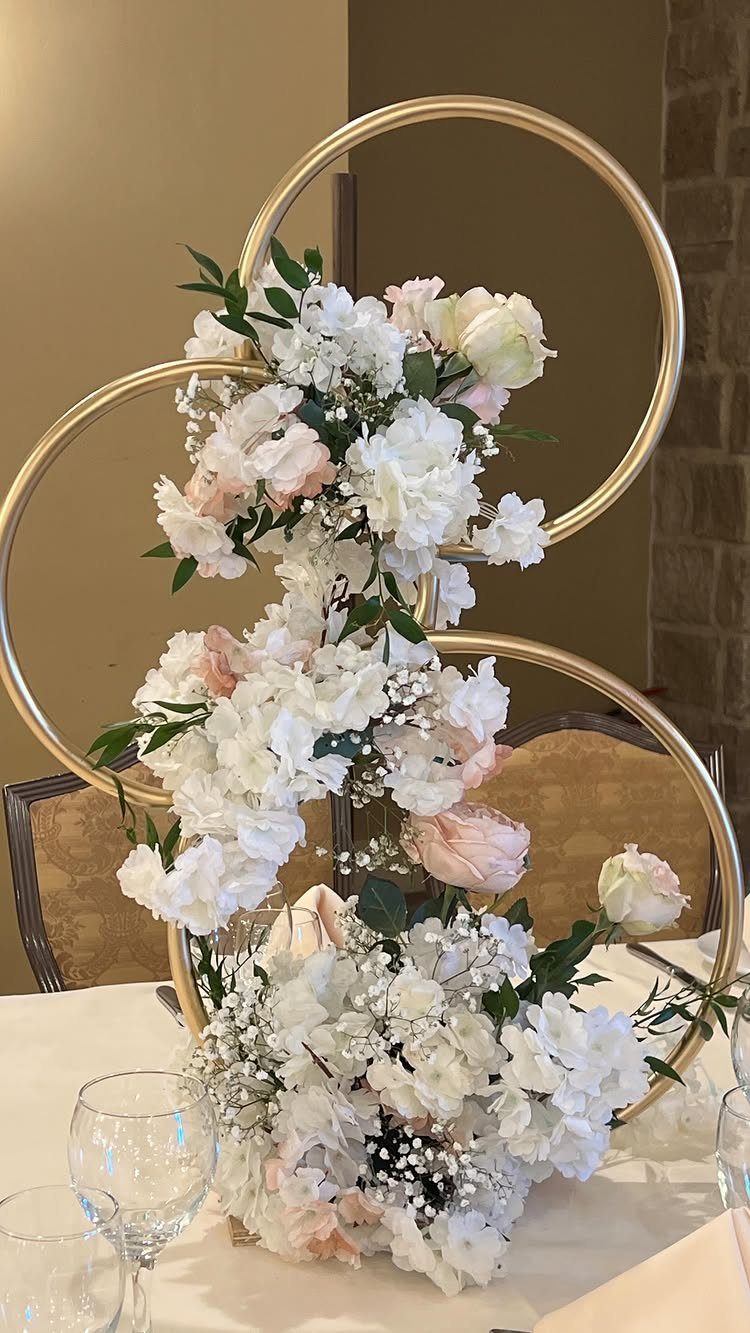 Interlocking gold hoops decorated with white and pink roses as a wedding centerpiece.