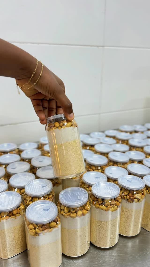 Hand holding a glass jar of layered grains among many similar jars.