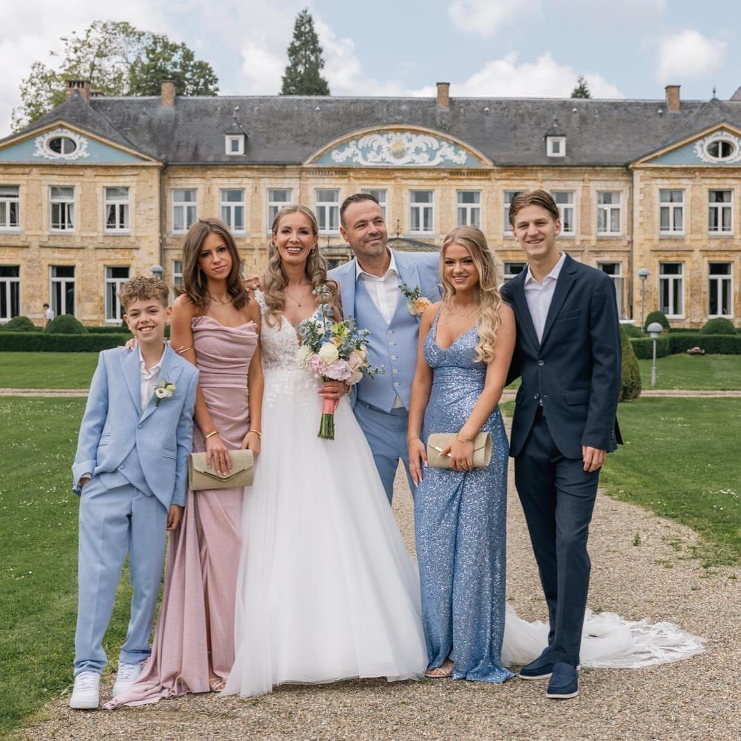 Wedding party posing for portraits in front of a grand stone manor house.