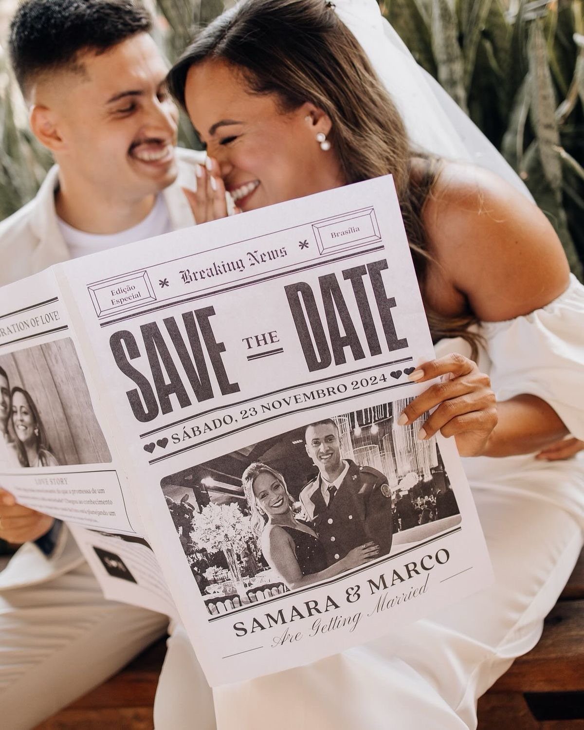 Couple holding a newspaper-style save the date wedding announcement outdoors in white clothing