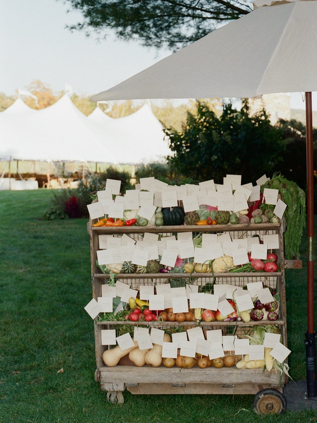Wooden cart filled with autumn produce and white name tags for wedding guests.