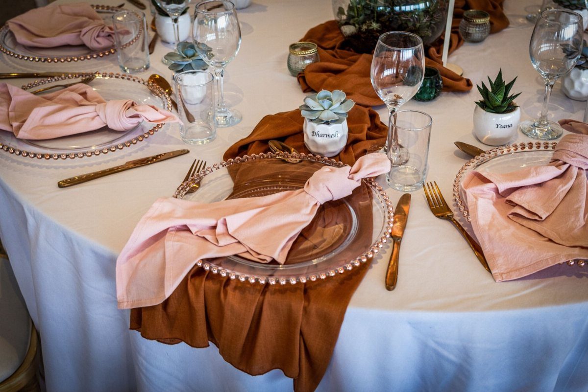 Succulent plants in small white pots used as place cards on a wedding table.