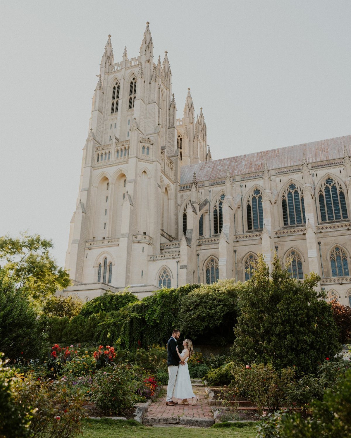 Wedding couple in a garden before the Gothic architecture of National Cathedral