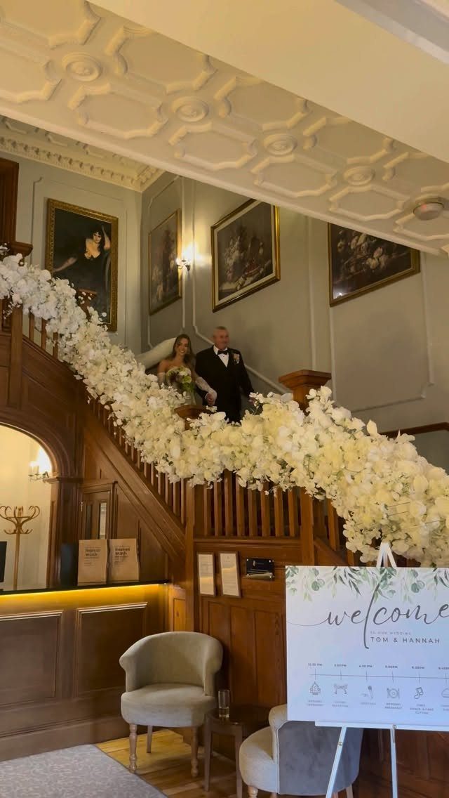 Bride and groom on a wooden staircase adorned with white floral garlands