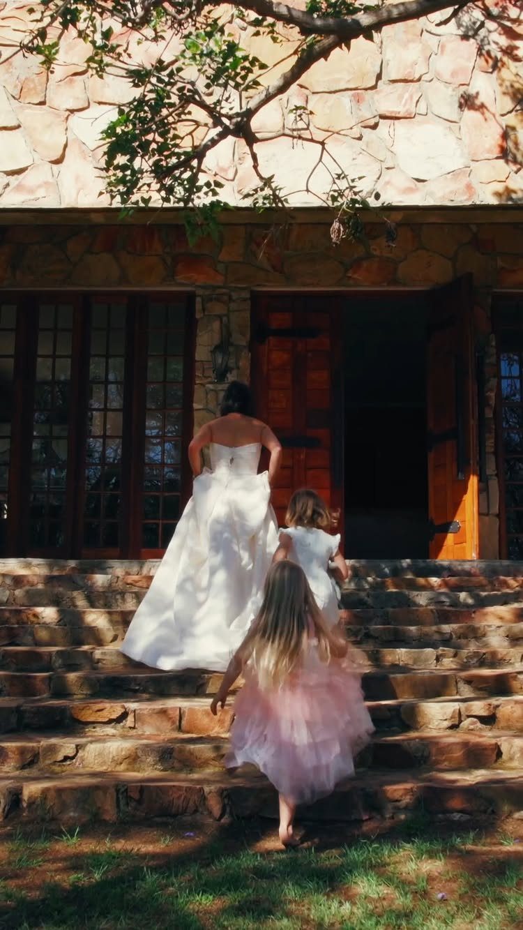 Bride and flower girls walking up stone steps toward a stone castle venue.