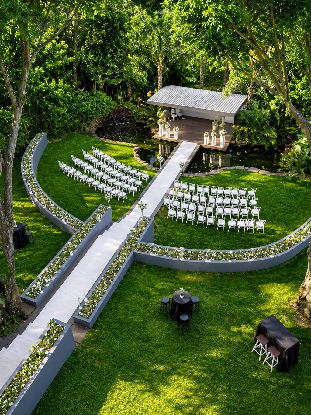 Outdoor wedding ceremony setup with white chairs and altar in a lush garden