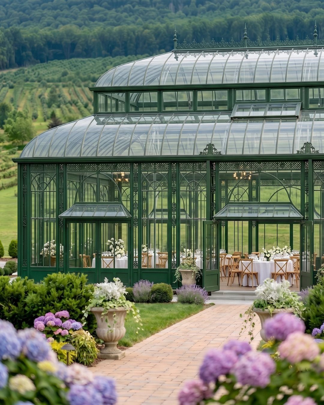 Green glass conservatory wedding venue with dining tables, surrounded by lush gardens and mountains.