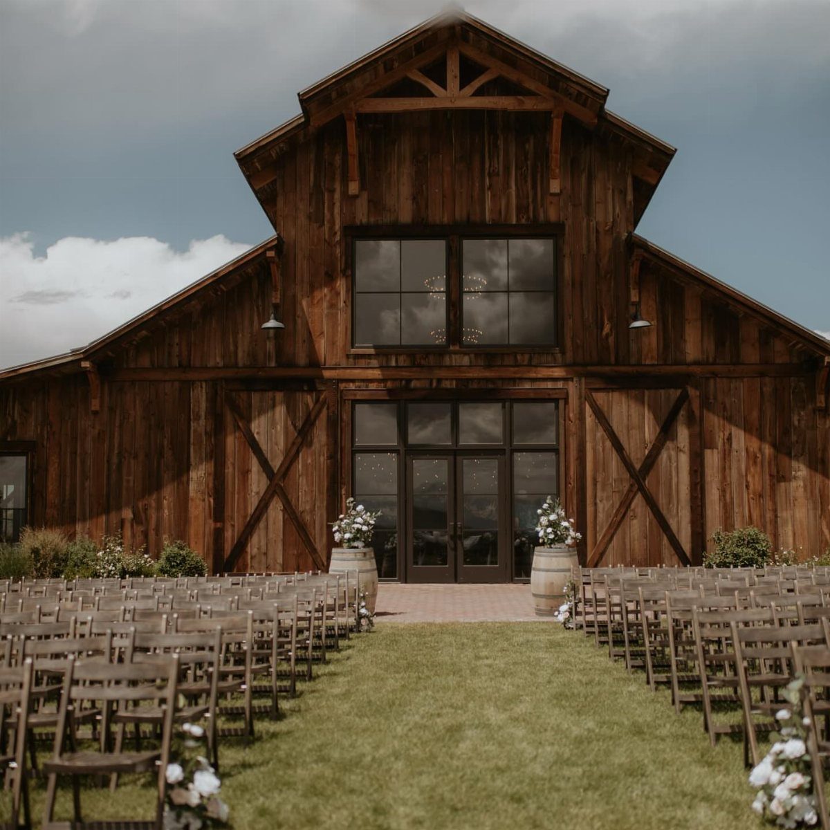 Rustic wooden barn wedding venue with rows of chairs on a green lawn.