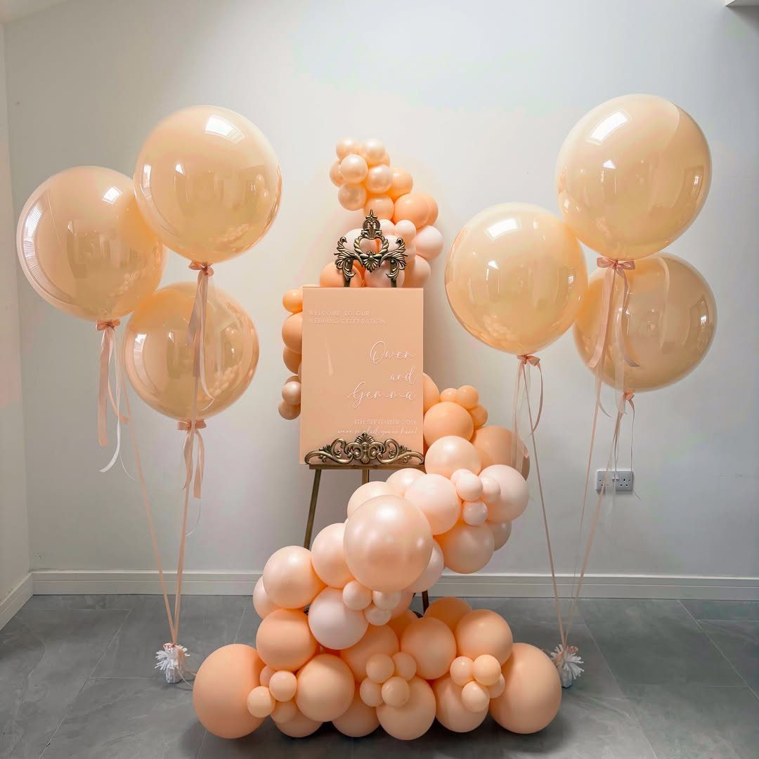 Peach balloon decor featuring floating balloons and a floor cluster around a sign.