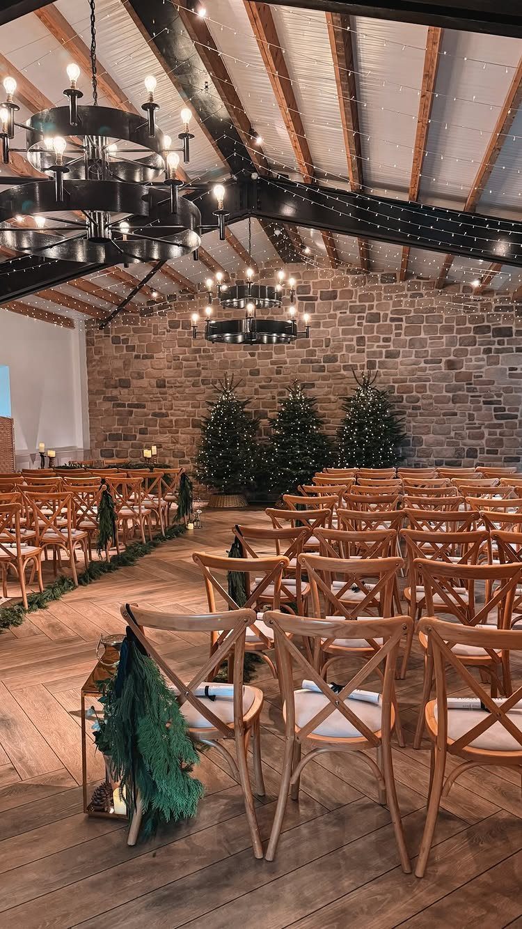 Rustic wedding ceremony venue with wooden chairs, stone walls, and winter greenery decorations.