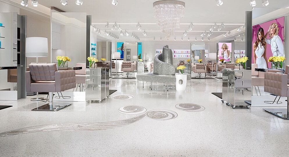 Luxurious beauty salon with mauve chairs, white floors, and a crystal chandelier.