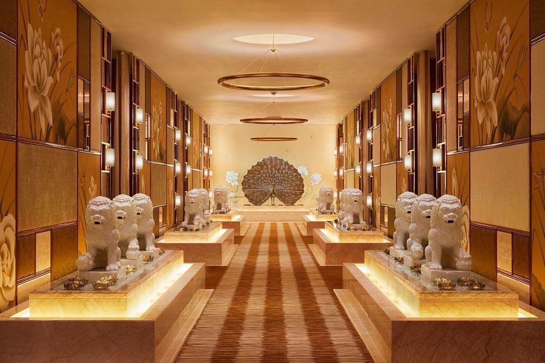 Luxurious gold hallway with white lion statues and ornate floral wall panels.